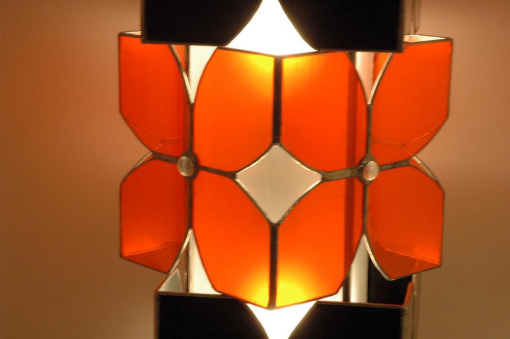 Vitraux oranges et noirs pour cette lampe à poser. Equipée de deux ampoules elle constitue une source de lumière intéressante en lampe d'appoint intégrée à la déco, sur un bureau ou une table de chevet.